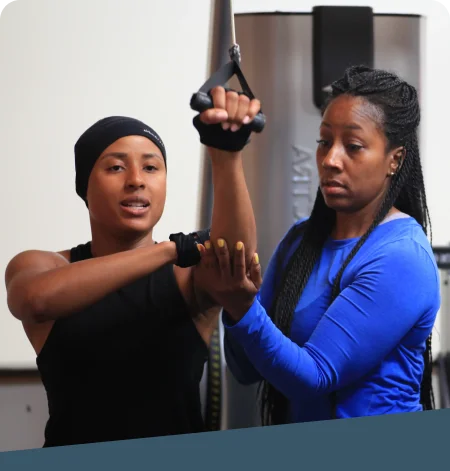 Female trainer spotting a woman's weight training form